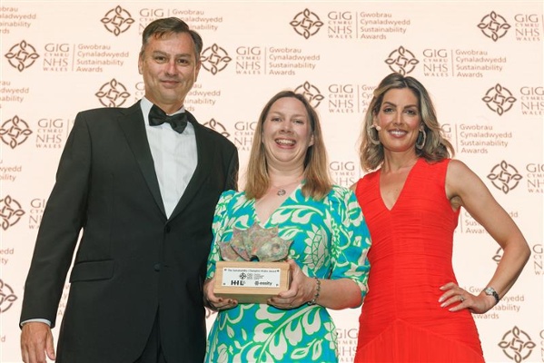 Image shows a woman holding an award alongside a man and woman