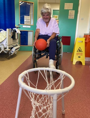 Image shows a woman throwing a basketball into a net