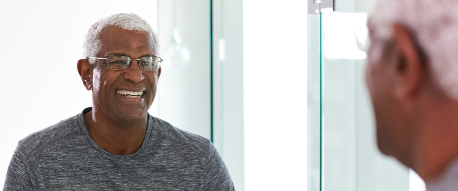 Image shows man smiling at his reflection in the mirror.