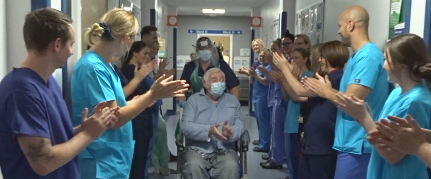 Danny Egan, in a wheelchair, applauds staff who are clapping him