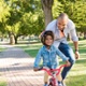 An image of a child on a bike with support from a parent