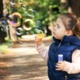 A young girl blowing bubbles in a park.