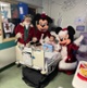 Santa, Mickey and Minnie Mouse with a smiling child in a hospital bed