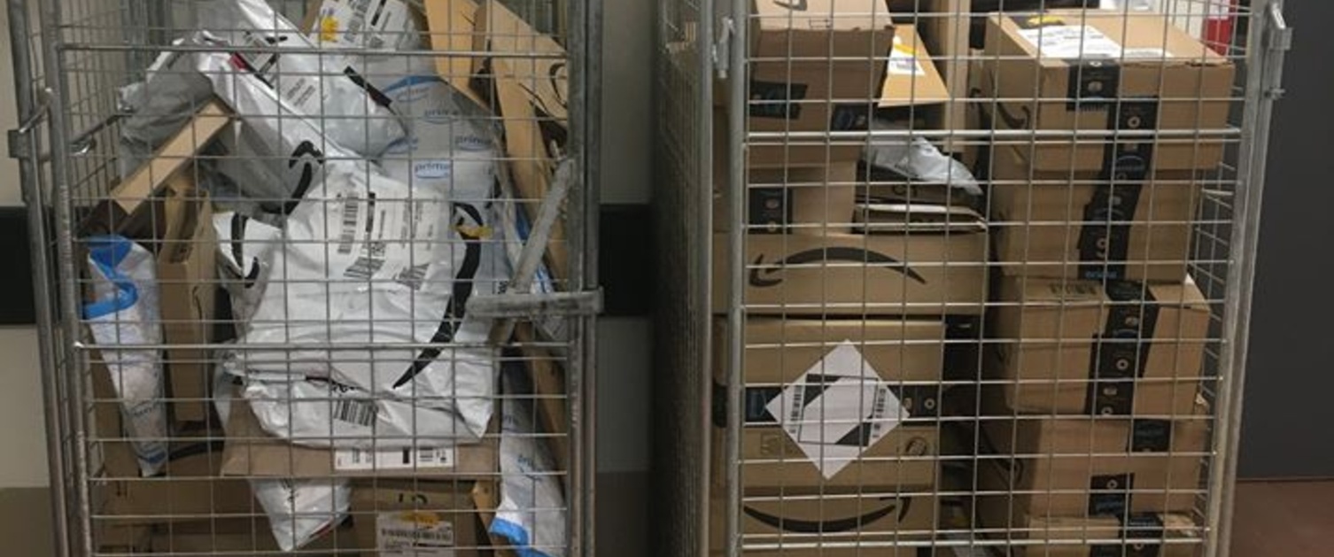 Image shows two metal cages full of Amazon parcels.