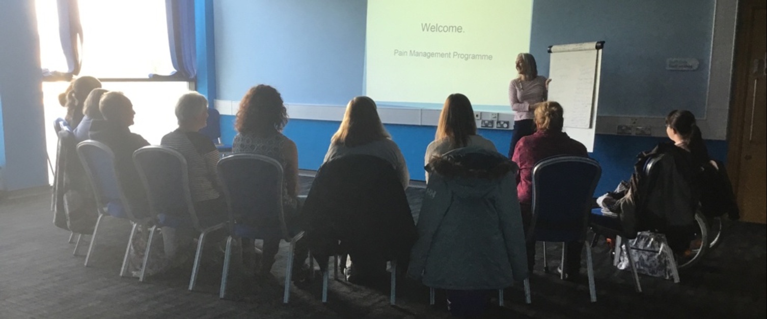 An image of a group of people sat watching a presentation in
the Pain Management Programme. 