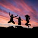 An image of kids jumping in the air with a sunset behind them