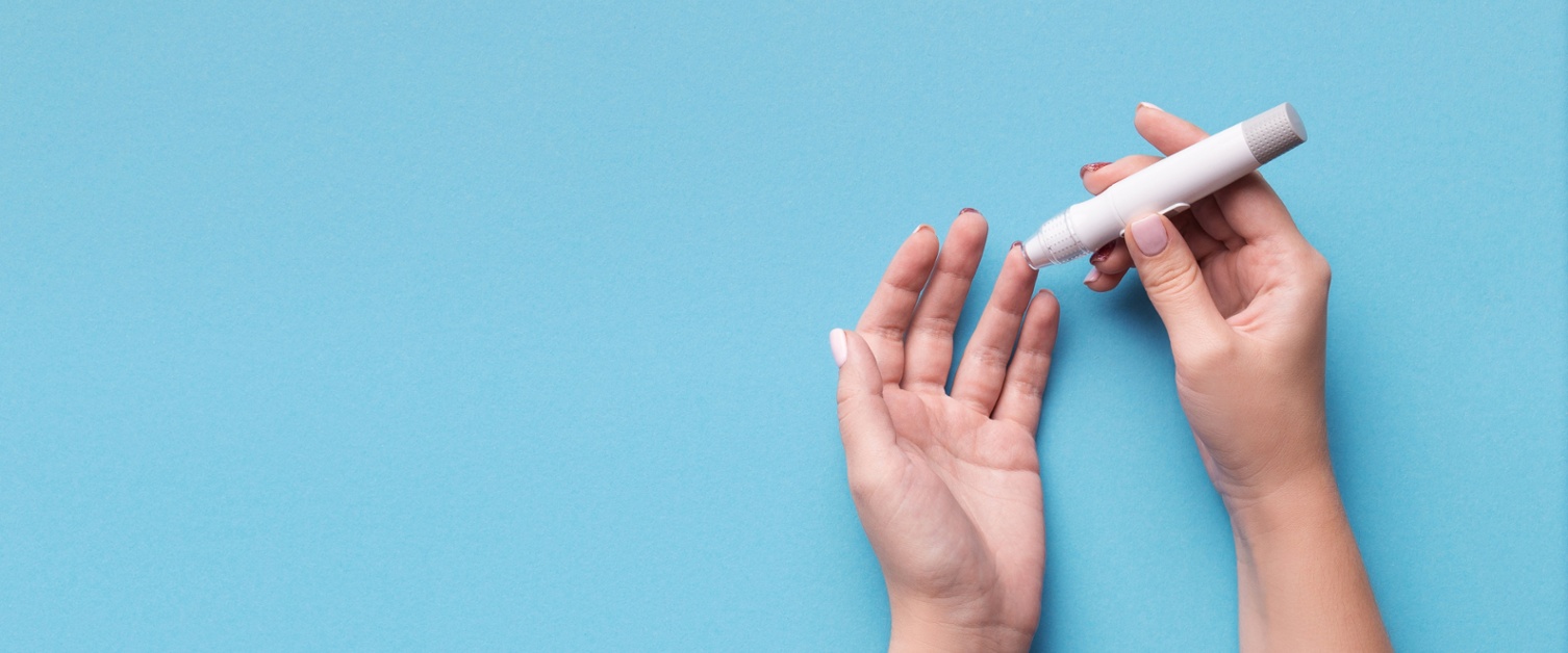 Image shows two hands. The person is doing a finger prick test for blood glucose levels.