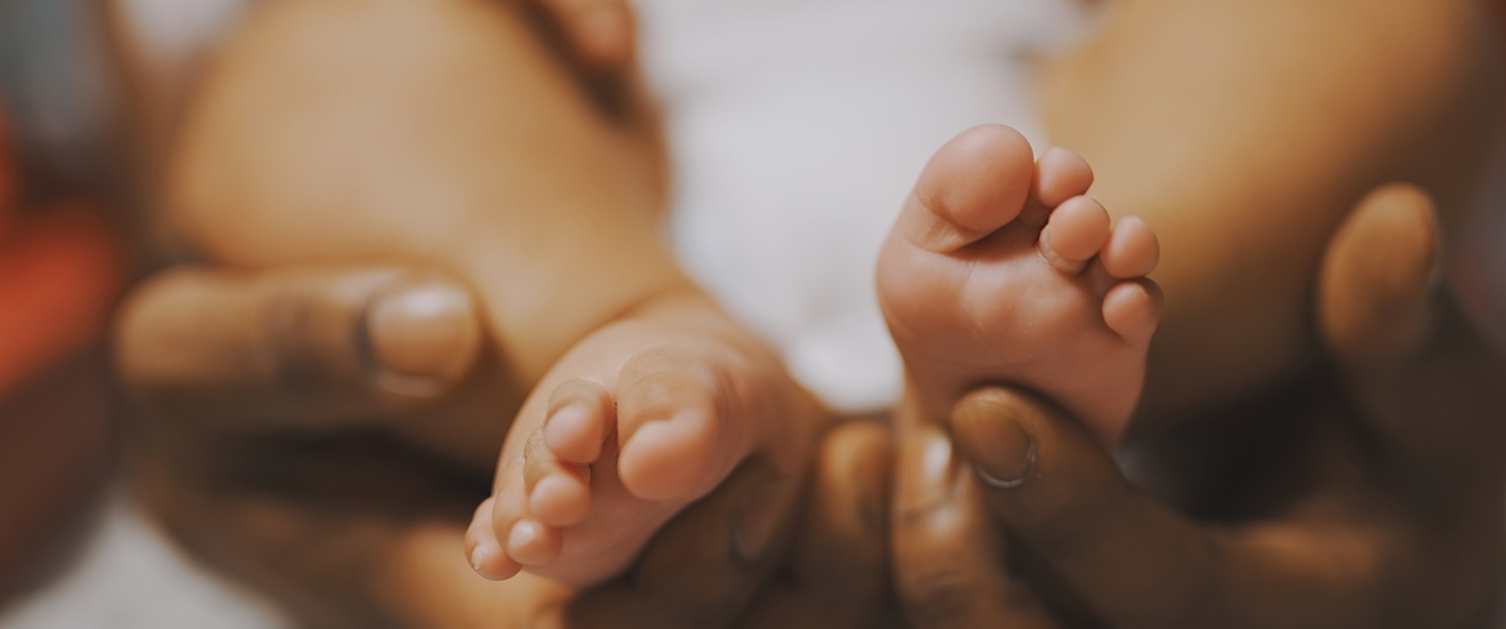 An image of hands holding baby feet.
