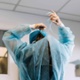 Image shows a surgeon from behind tying their gown at the neck.