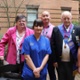 Group shot of patient Jenny Young and husband Colin with hospital staff, standing in courtyard garden at Morriston Hospital.
