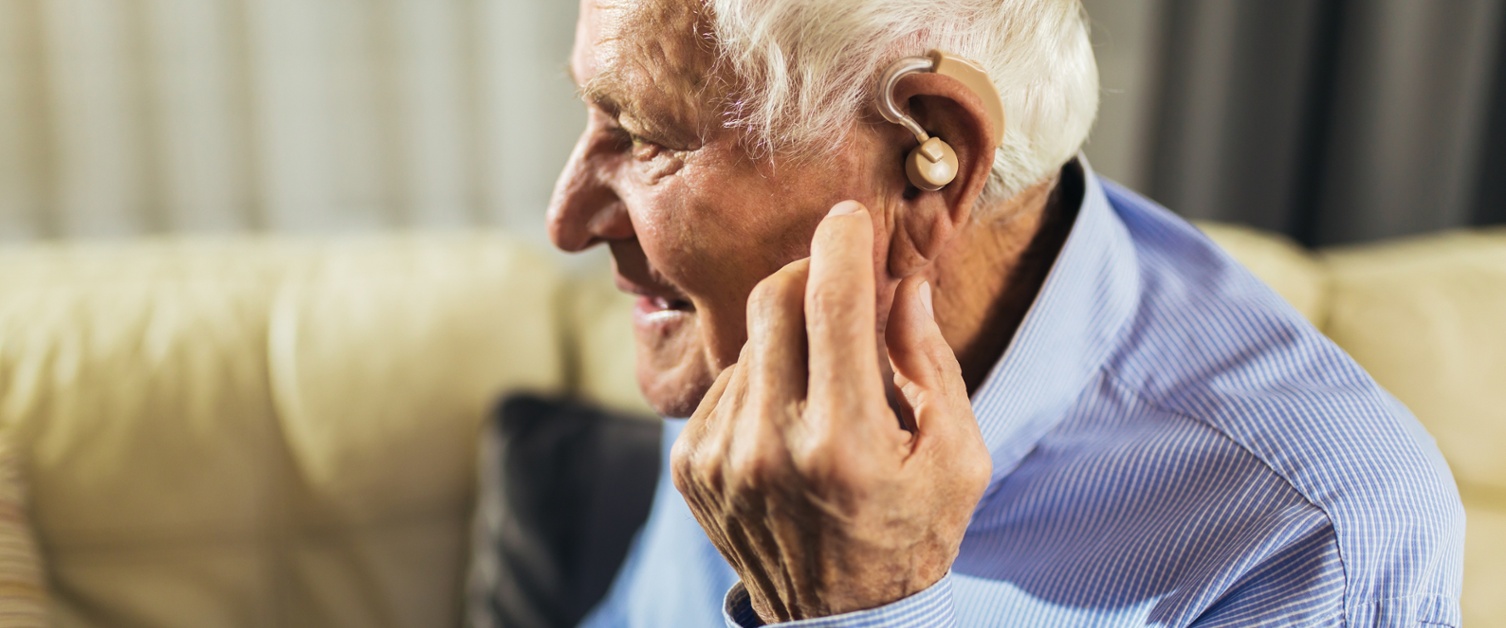 Image shows man with a hearing aid in their ear.