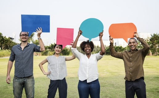 Picture of four people holding up pieces of paper in the shape of speech bubbles.