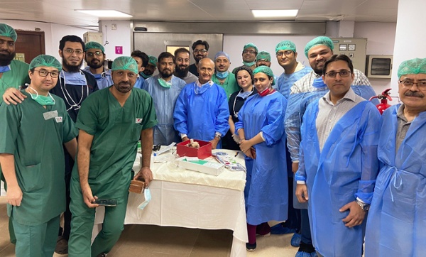 Image shows a group of surgeons wearing scrubs in an operating theatre