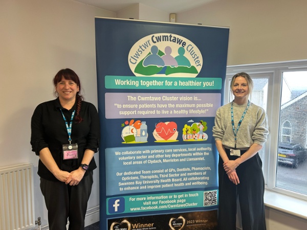 Aimee and Katy stood next to a Cwmtawe Cluster banner