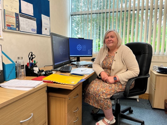 Image shows a woman sitting at a desk