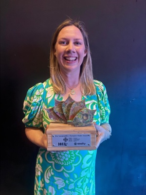 Image shows a woman holding an award