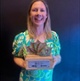 Image shows a woman holding an award