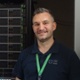 Image shows a man standing alongside a stack of computer servers.