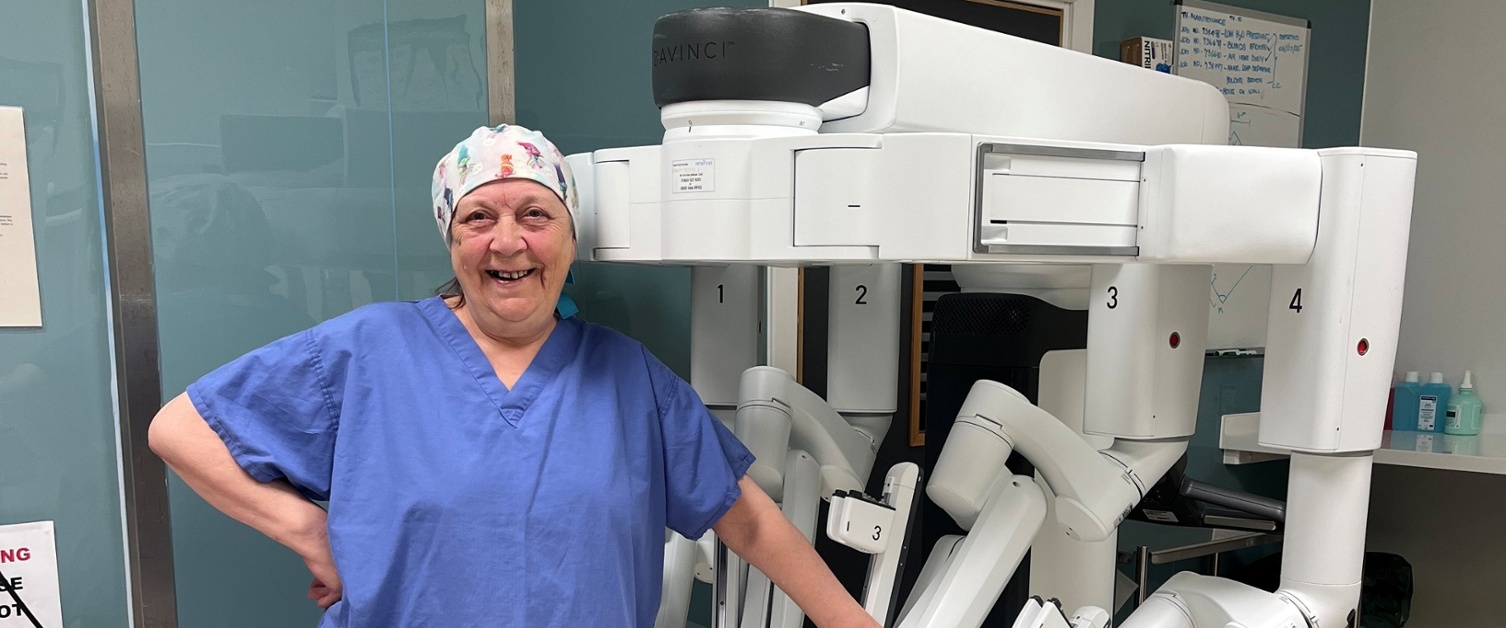 Image shows a woman stood next to a medical machine