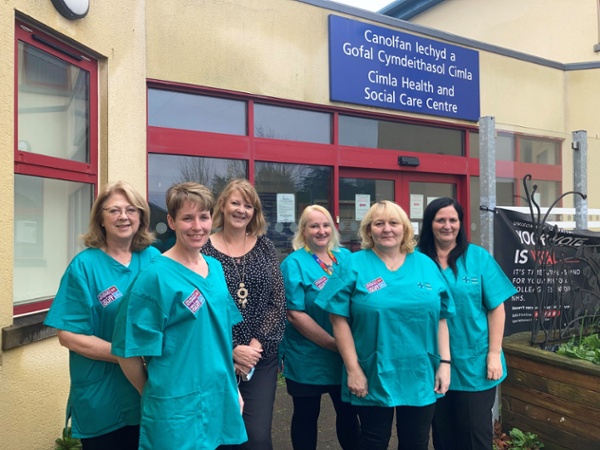 A group of women wearing scrubs standing outside a hospital