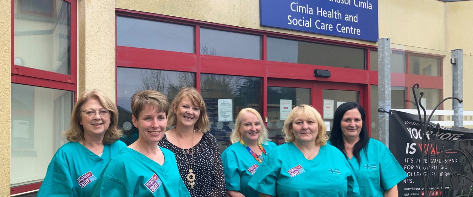 A group of women wearing scrubs standing outside a hospital