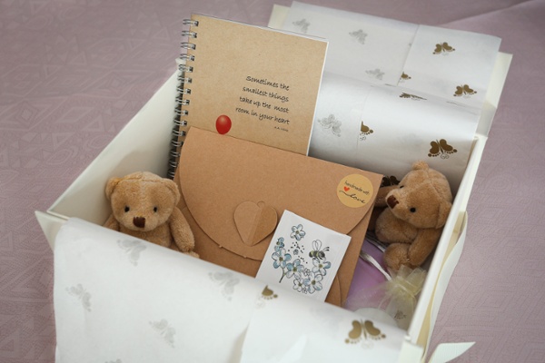 A small box containing a notebook, an envelope and two cuddly toys