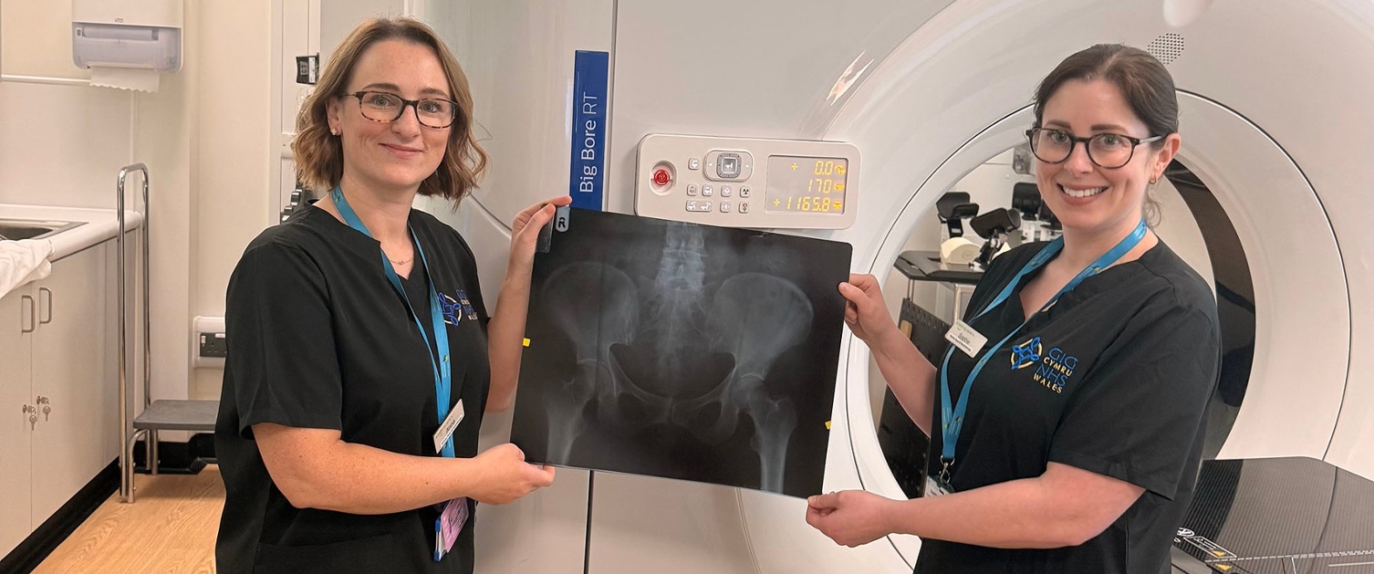 Image shows two people holding an X-ray in a radiotherapy room.