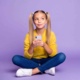 Image of young girl sat on floor holding mobile phone.