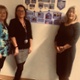 Image shows three women standing next to photos