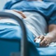 Image shows a patient in a hospital bed.