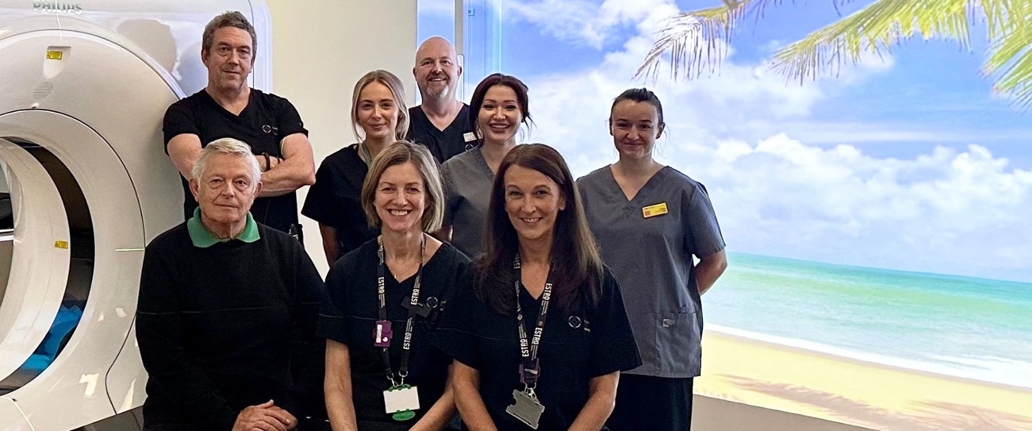 Image shows a group of people alongside a CT scanner.