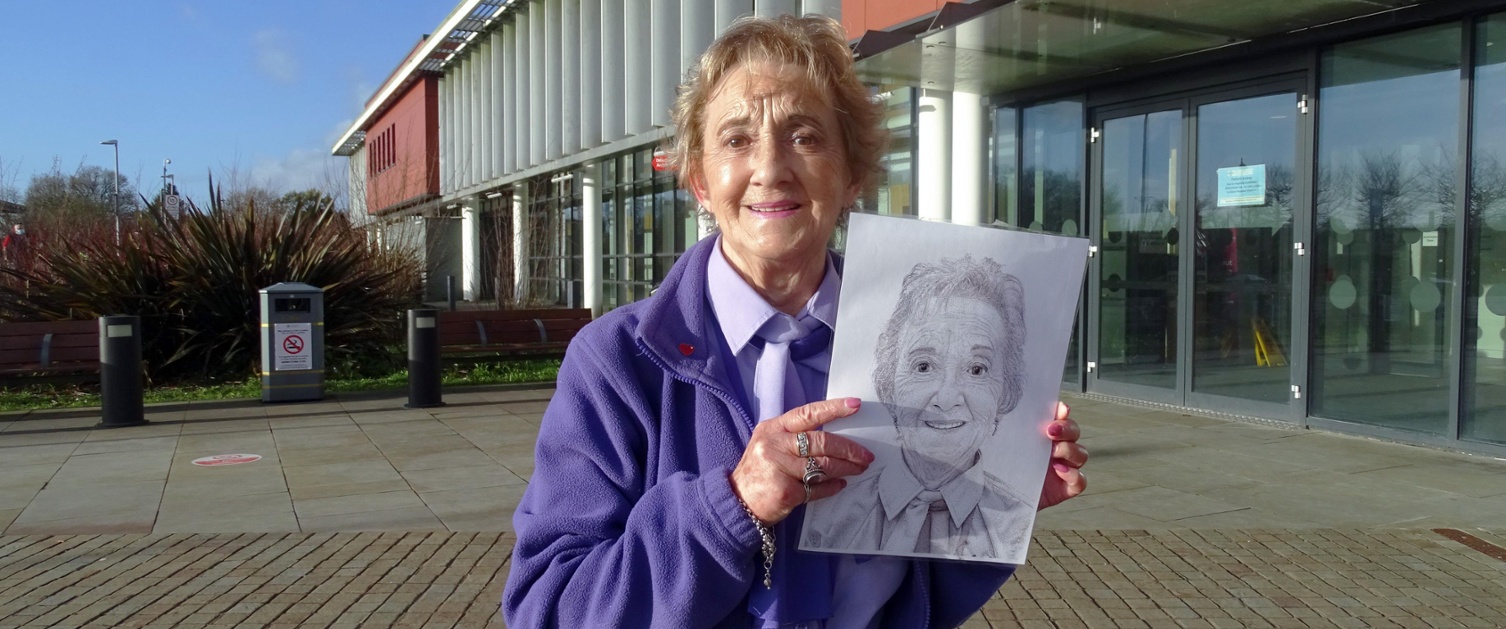 Woman in lilac top standing outside a hospital