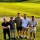 A group of golfers, standing in the sunshine on a golf course.