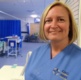 A nurse standing in a ward smiling at the camera.