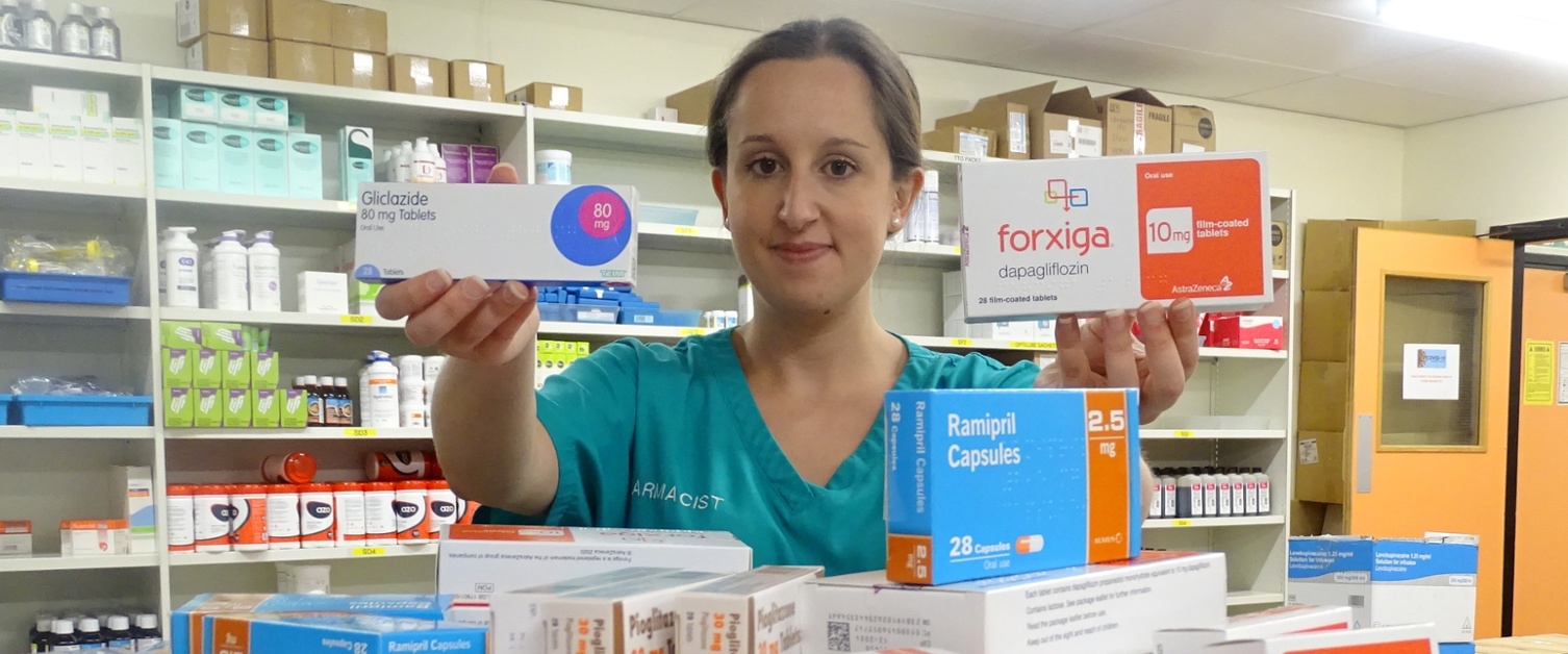 A hospital pharmacist holding boxes of medication.