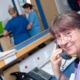 A nurse smiling at the camera whilst on the phone with two nurses in the background.