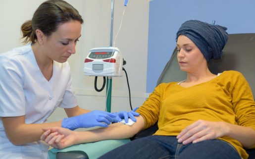 A patient on a reclining bed has a needle inserted into her arm