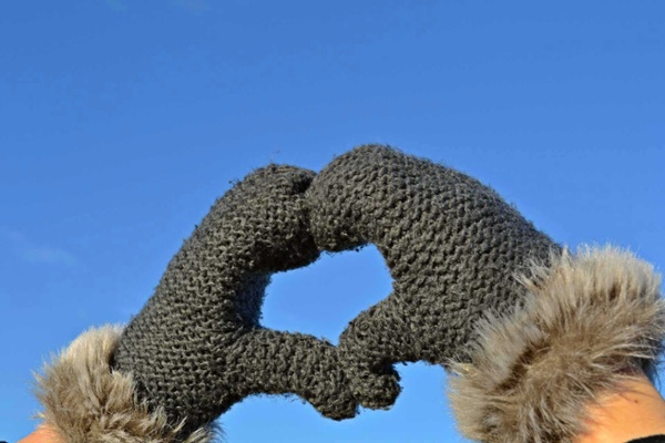 Hands in mittens with fingers forming a heart shape.