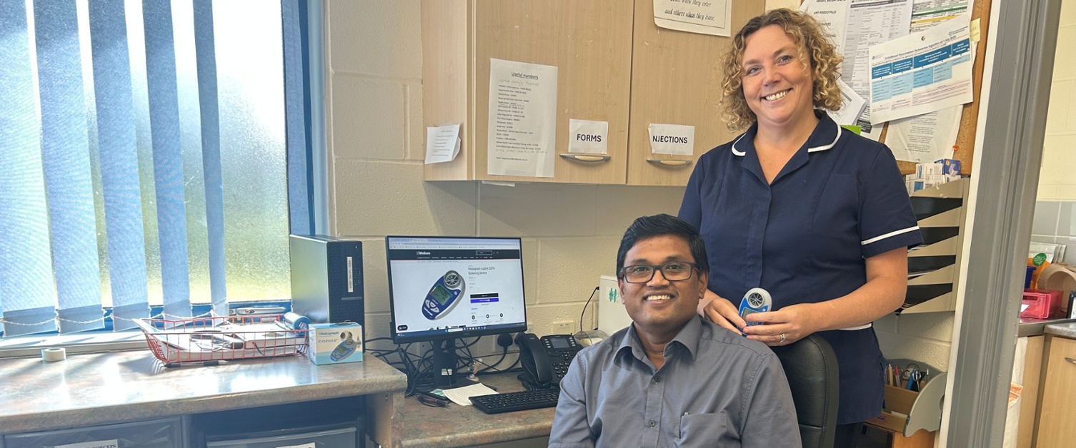 Kannan sat down and Rebecca stood behind him holding the device