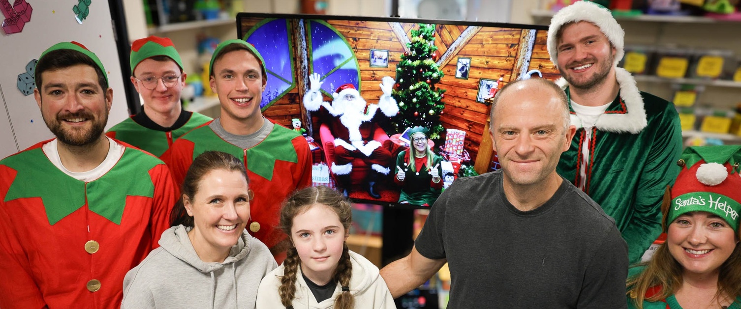 Image shows people dressed as elves with a young hospital patient.