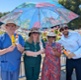 A group of hospital staff, wearing sun hats and sheltering under a parasol in the sunshine