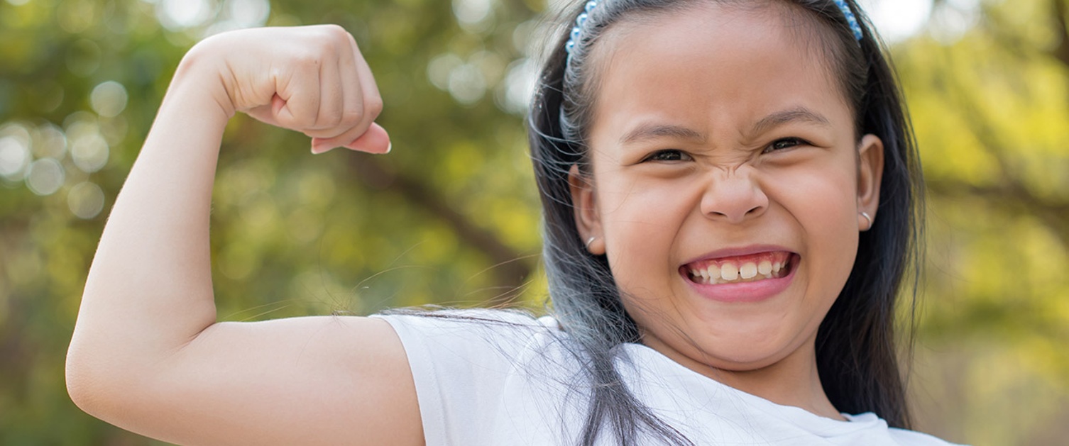 Image shows smiling girl doing bicep curl to demonstrate strength.
