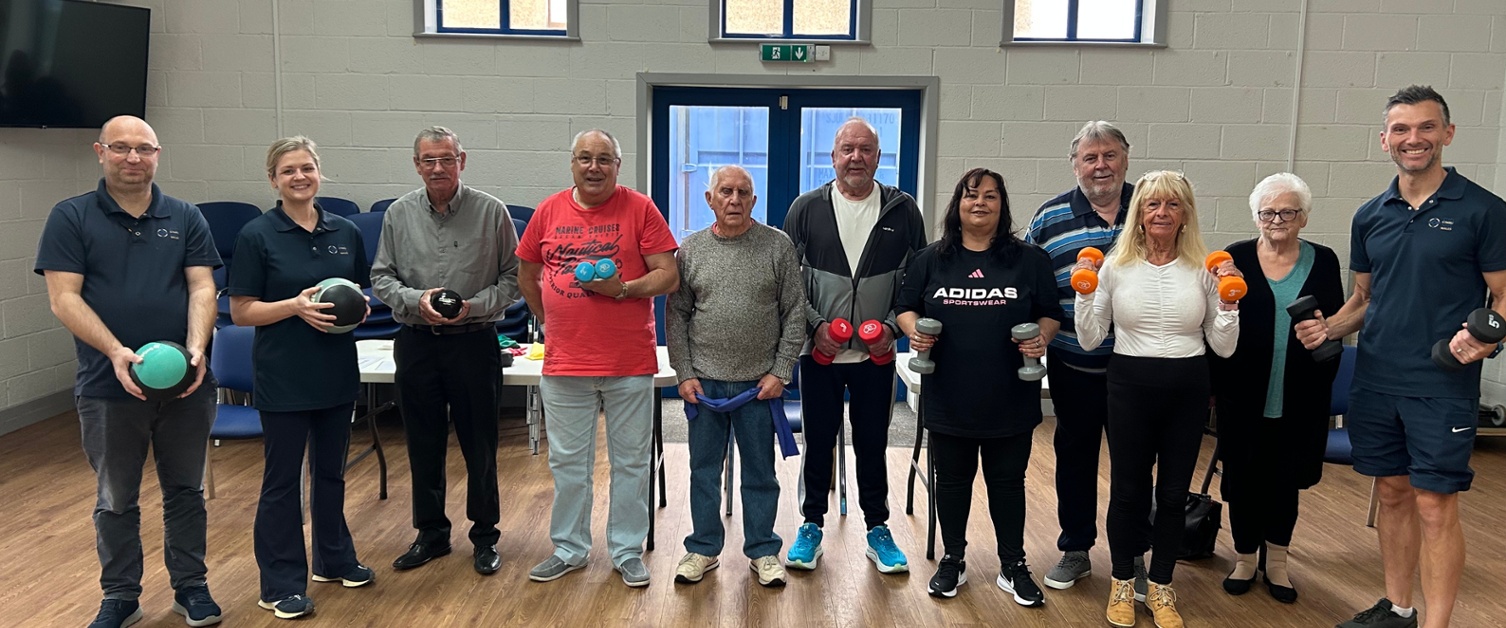 Members of staff and patients holding exercise equipment