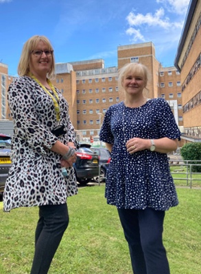 Image shows two women standing outside a hospital