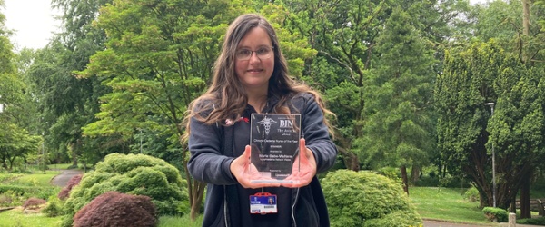 Image shows a woman holding an award