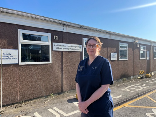 Image shows a woman standing in front of a building