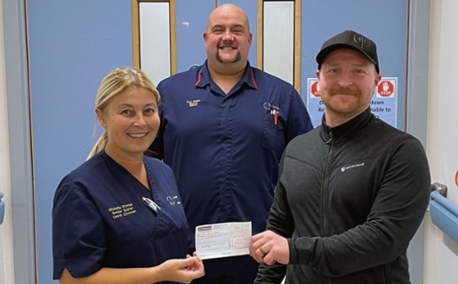 Image shows three people in a hospital, two of them holding a cheque
