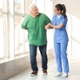 Image shows a man walking with a nurse helping him