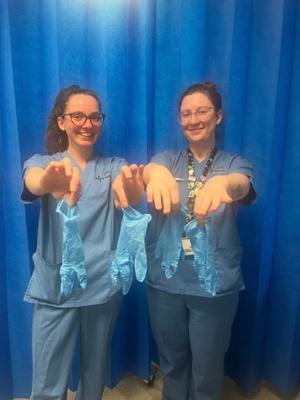 Image shows two clinicians holding blue gloves