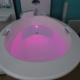 A birth pool with the water lit up pink.